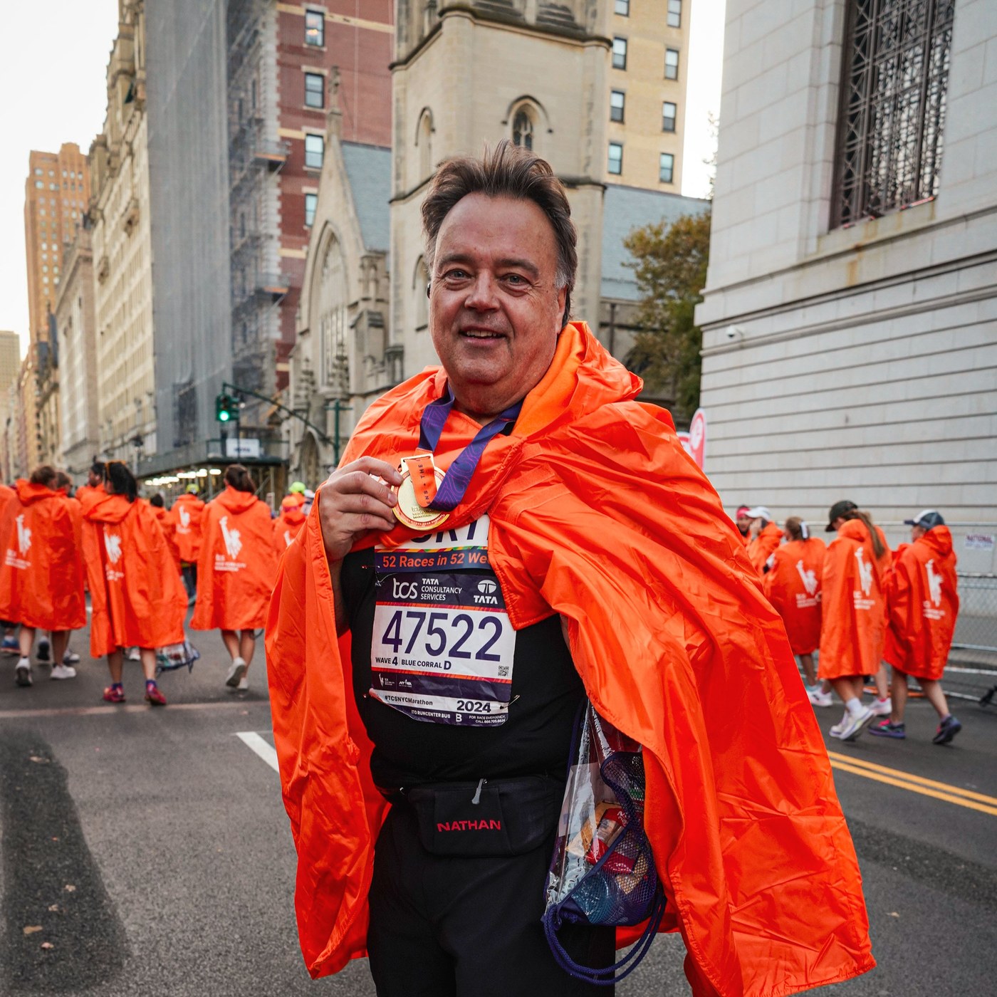 Curtis wrapped in an orange finisher cape with his medal in New York
