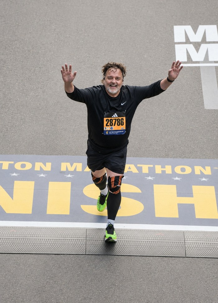 Curtis jumping for joy at the Boston Marathon finish