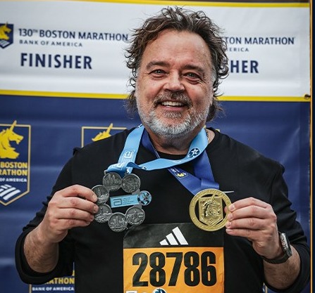 Curtis Stewart at the Boston Marathon finish, holding his Abbott World Marathon Majors Six Star Medal