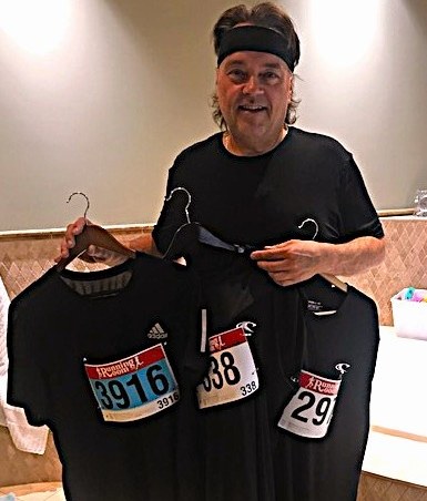 Curtis holding race shirts and bibs from early events